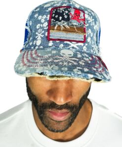 Man wearing a decorated denim cap with skull and floral patterns.