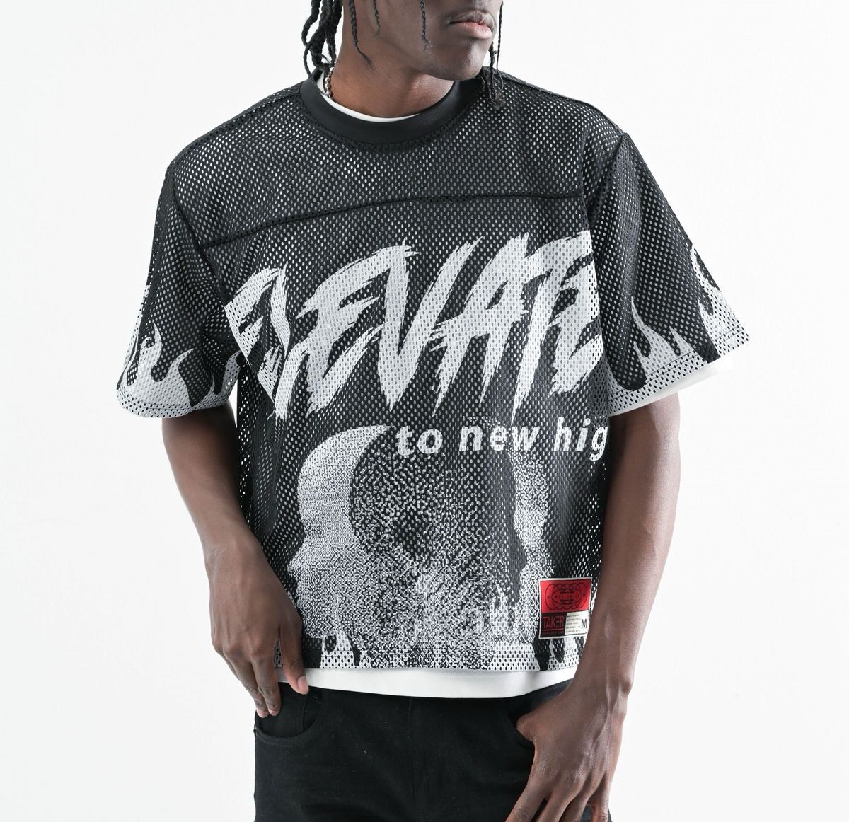 Man wearing a black graphic mesh shirt with bold white text and skull design.