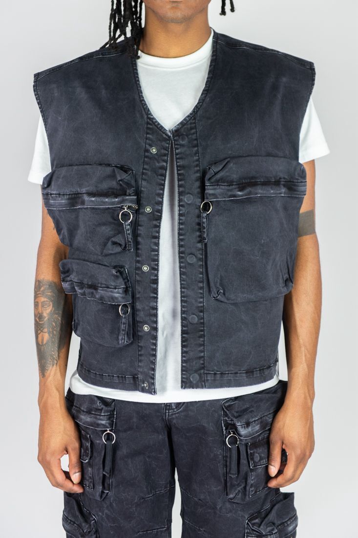 Black utility vest with multiple zippered pockets worn over a white t-shirt.