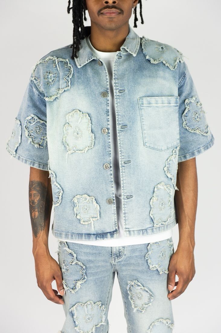 Distressed denim jacket with matching shorts, featuring frayed patches and a light wash.