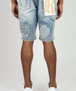 Back view of distressed denim shorts with patch details worn by a person.