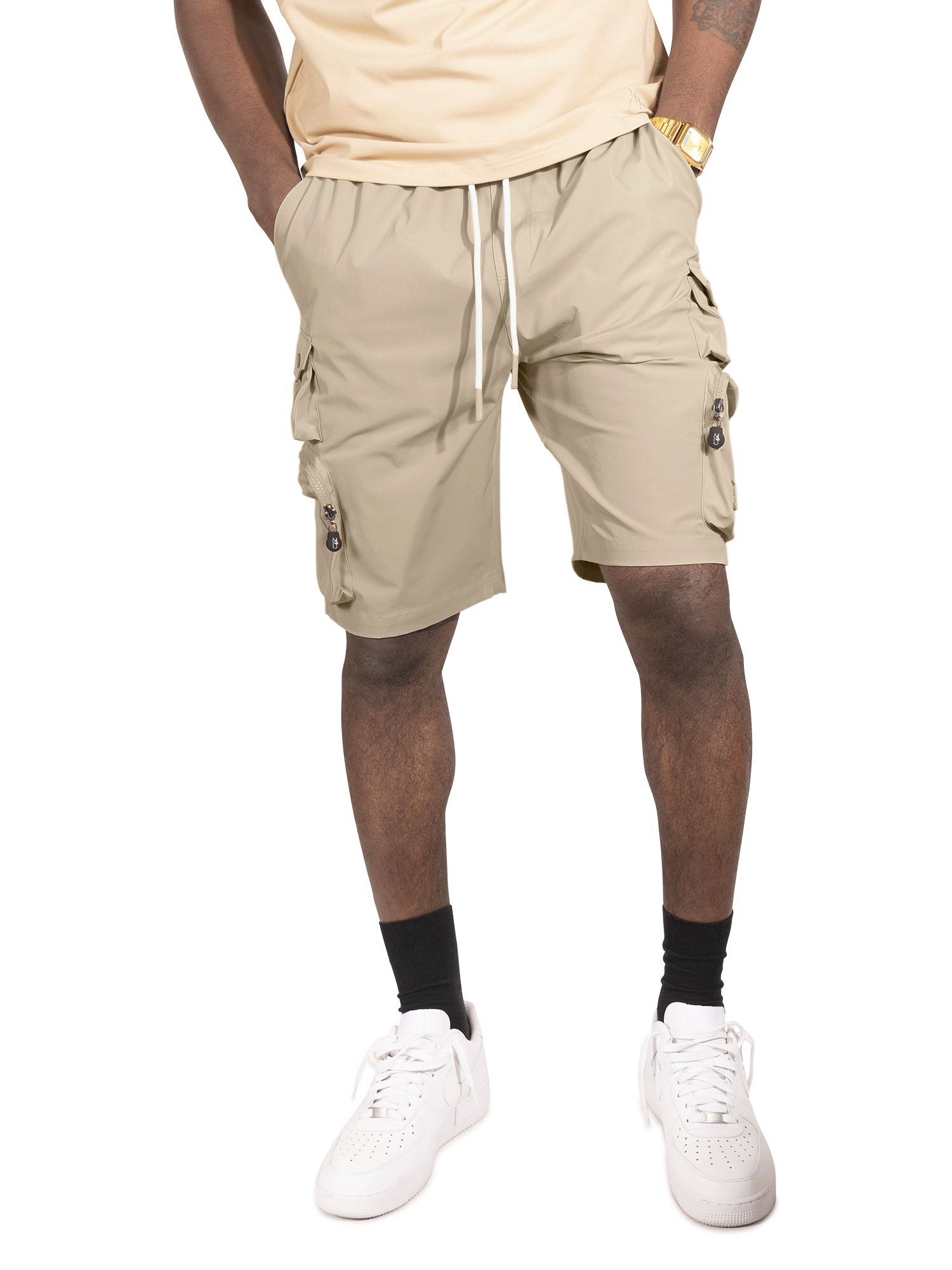 Man wearing beige cargo shorts with pockets and white sneakers.